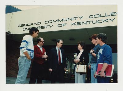 A group of people stand talking in front of Ashland Community College