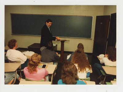 A class listens to a male professor