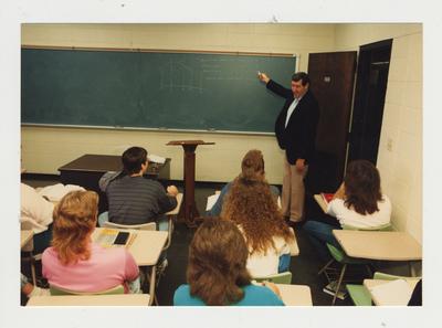 A class listens to a male professor