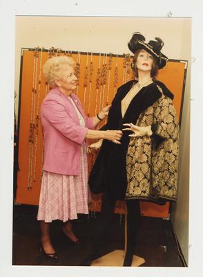 A woman examines clothes on a mannequin