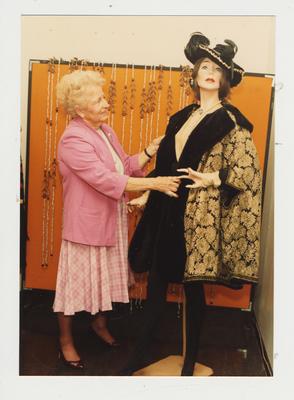 A woman examines clothes on a mannequin