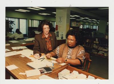 A woman helps an unidentified African - American woman