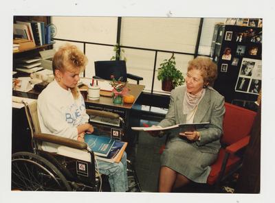 Marie Brake (right), Coordinator of Handicapped Student Services, helps an unidentified female student in her office