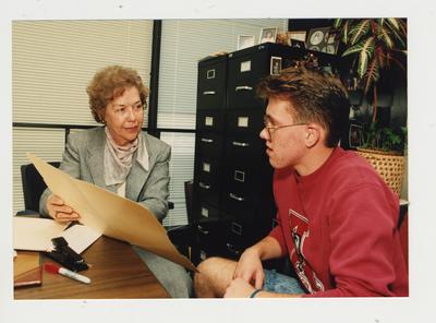 Marie Brake (right), Coordinator of Handicapped Student Services, helps an unidentified male student in her office