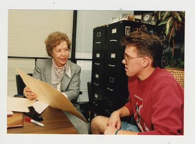 Marie Brake (right), Coordinator of Handicapped Student Services, helps an unidentified male student in her office