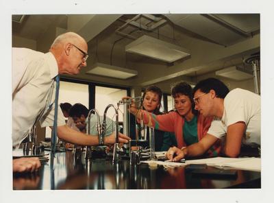 A male professor helps students perform an experiment