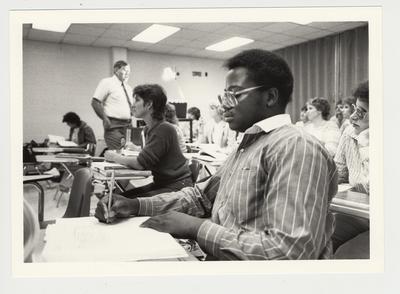 An unidentified African - American male student and others take notes during a class in at Elizabethtown Community College