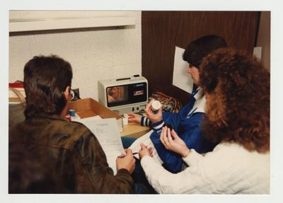 Students look at an audio visual machine which has visual and a cassette audio tape for class use in the library