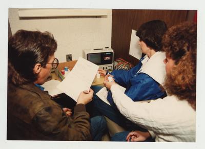 Students look at an audio visual machine which has visual and a cassette audio tape for class use in the library
