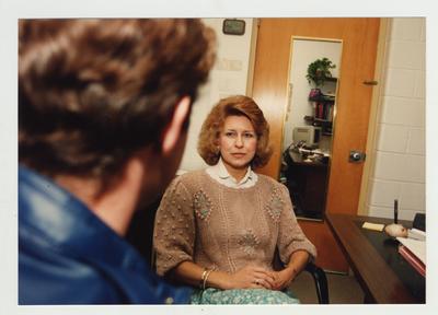 A male student speaks with an unidentified woman in her office