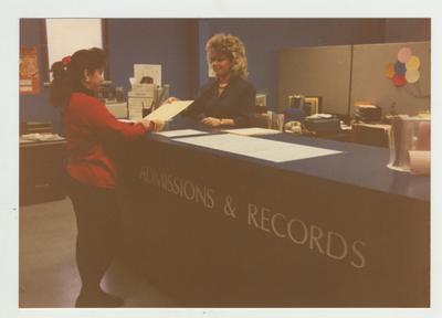A woman helps a female student in the Admissions and Records office