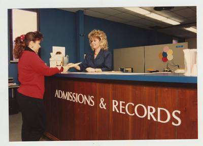 A woman helps a female student in the Admissions and Records office