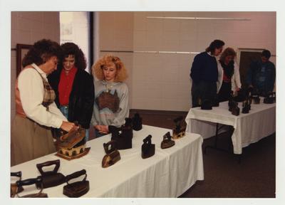 Men and women look at antique household irons