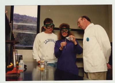A male Chemistry professor watches students perform an experiment