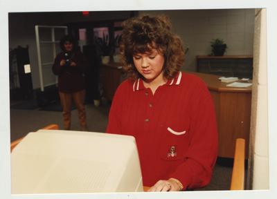A female student uses a computer in the library to locate books