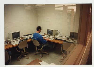 A male student types on a computer in the computer lab located in the library