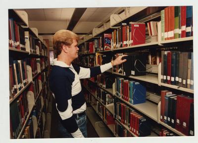 A male student looks for a book in the library