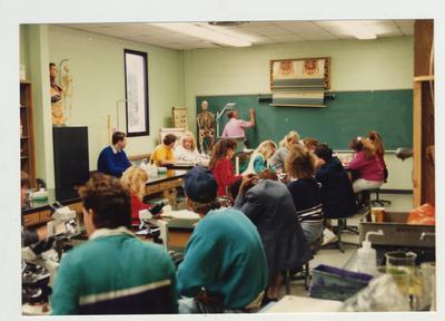 A male professor helps students in a laboratory classroom