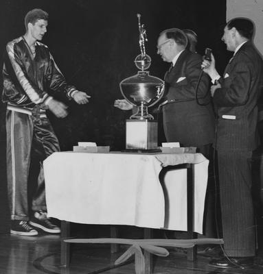 UK winning the Southeastern Conference championship tournament in 1950; pictured is Bill Spivey accepting award from Governor Earle Clements, trophy stands on table between them. Received June 13, 1959 from Cincinnati Enquirer