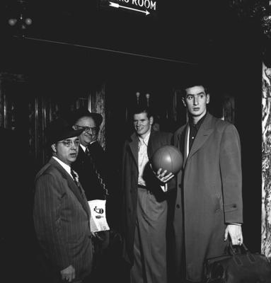 Jim Line (2nd from right) and Alex Groza (far right) are standing with two unidentified guests at party honoring coach Adolph Rupp and the basketball team