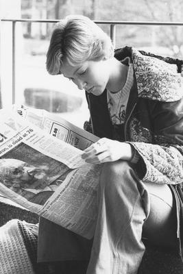 Unidentified student reading the December 11, 1977 Kentucky Kernel, which features a front-page article on the death of basketball coach Adolph Rupp