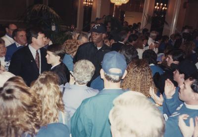 Group of fans and supporters at a downtown event for UK basketball; in the photo are players Travis Ford (left center, black wind breaker jacket) and Jamal Mashburn (tall man in center, wearing 
