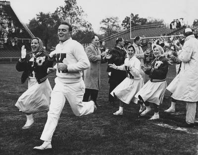 Unidentified UK cheerleaders running onto Stoll Field before game. Received December of 1960 from Public Relations