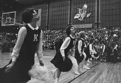 Unidentified cheerleaders at a unidentified basketball game; opponent's cheerleaders have 