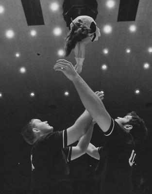 Two unidentified UK male and one female cheerleaders at basketball game. Photo appears on page 235 in the 1969 Kentuckian