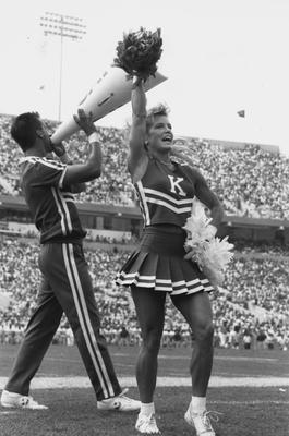 Unidentified male cheerleader is standing left and Amy Boyanowski is standing right leading a cheer at Commonwealth Stadium