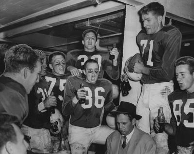 Coach Paul Bryant (seated, center) and football team members celebrate victory over Cincinnati; pictured are Tom Fillian (21), Bobby Fry (71), O. E. Philpot (36), Clark Ratcliffe (30), Frank Fuller (75) and Jack Cassons (85); photographer:  Herb Heise, Cincinnati Enquirer. Received June 13, 1959 from Cincinnati Enquirer