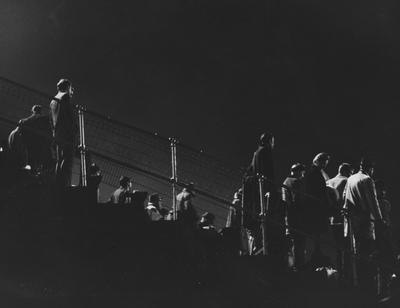 Fans standing in stadium watching a night football game. Photo appears on page 80 in the 1969 Kentuckian
