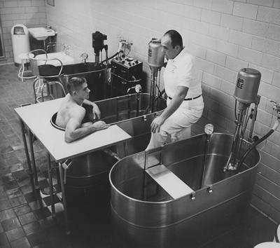 Unidentified UK football player in whirlpool talking with unidentified trainer