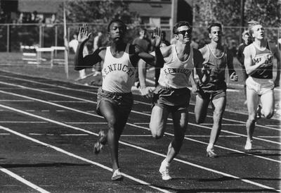 Two unidentified UK Men's Track team members and two unidentified opponents crossing finish line at track meet; photo appears on page 389 in the 1969 Kentuckian