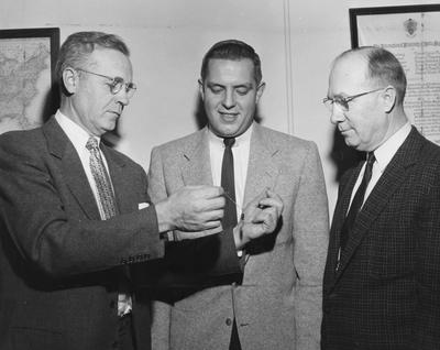 Unidentified senior (center) winner of the Delta Sigma Pi (Professional business fraternity) award; to the left is C. C. Carpenter, Dean of Commerce; man to the right is unidentified; photo appears on page 35 in the 1956-57 K-Book