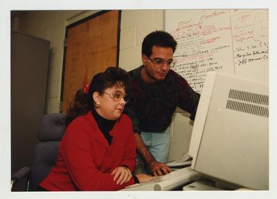 A man helps a woman with a computer