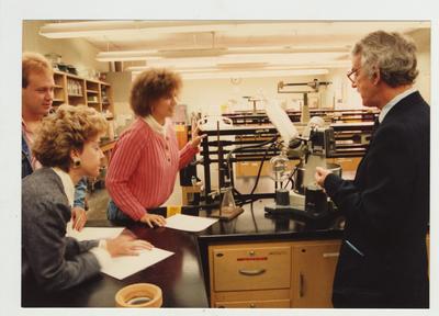 A male professor and his students look at a machine in a laboratory
