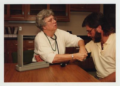 A woman taking a man's blood pressure