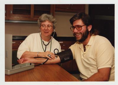 A woman taking a man's blood pressure
