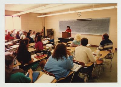 Students listen to a female professor during a classroom lecture