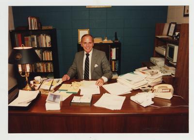 An unidentified man sits at his office desk