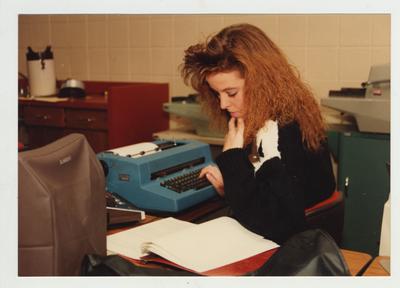 A female student types on a typewriter in a classroom