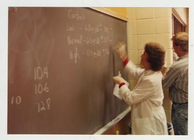 A professor writes on a blackboard