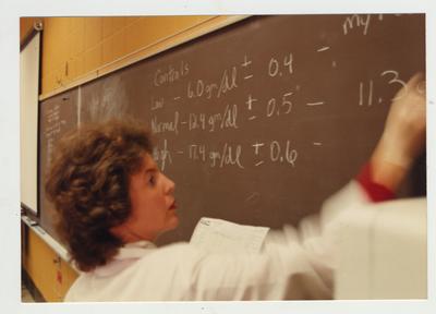A professor writes on a blackboard