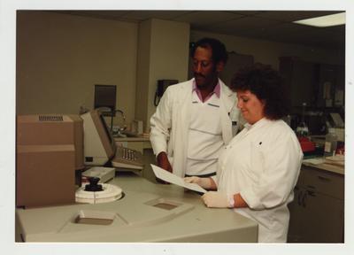 A woman and an African - American man work in a laboratory