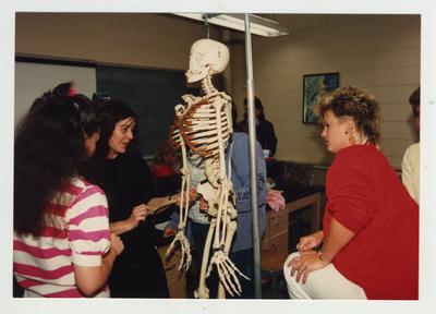 Female students look at a skeleton in a classroom