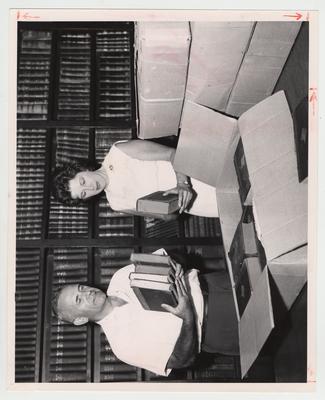 Wesley Patterson Garrigus (left), professor of Animal Husbandry, and Mary Powell Phelps (right) unpack books in the Agricultural Experiment Station Library