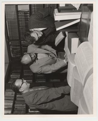From left to right: Ilham Kum, Dean Codle, and John Vigle look at books