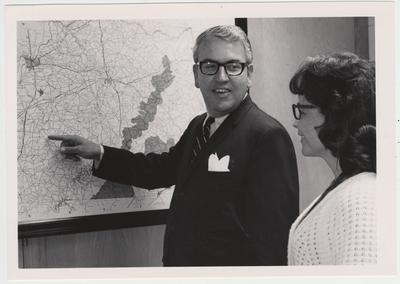 Charles Atcher, field representative of the University of Kentucky Libraries, points out Green County on a map of Kentucky to Mrs. Ann Stidham of the library director's office; Atcher coordinates a microfilming project in Green County with a microfilm operator of the Genealogical Society of the Church of Jesus Christ of the Latter Day Saints