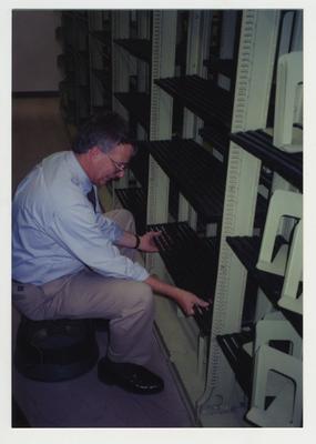 Bill Marshall cleaning shelving in core stacks for Special Collections to move into the 1929 M. I. King Building
